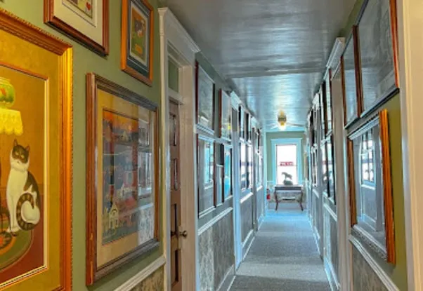 A long upstairs hallway lined on both sides with framed paintings and prints