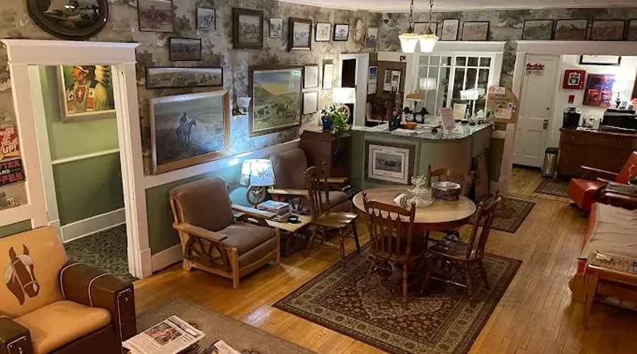 The lobby: a round wooden table, leather armchairs and walls hung with framed western art