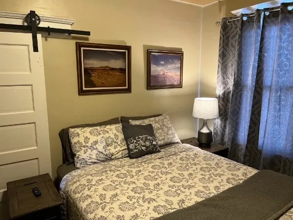 A second bedroom with a queen bed, a sliding barn door and landscape paintings