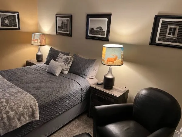 A bedroom in the three-bedroom unit with a leather armchair and black-and-white photographs