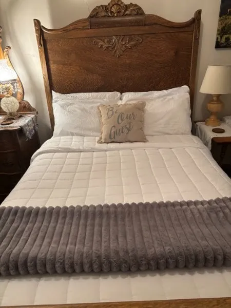 A carved wooden bed from the late 1880s with white bedding in room 31
