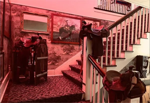 The main staircase with old saddles on the newel posts and a mural of horsemen