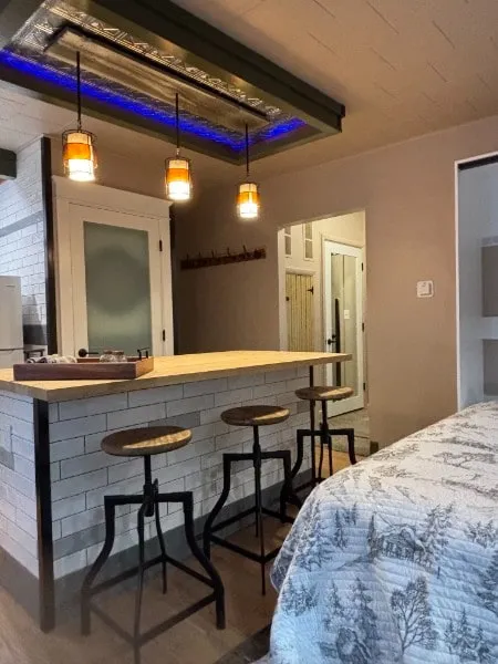 A studio with a tiled kitchen island, three stools and pendant lights