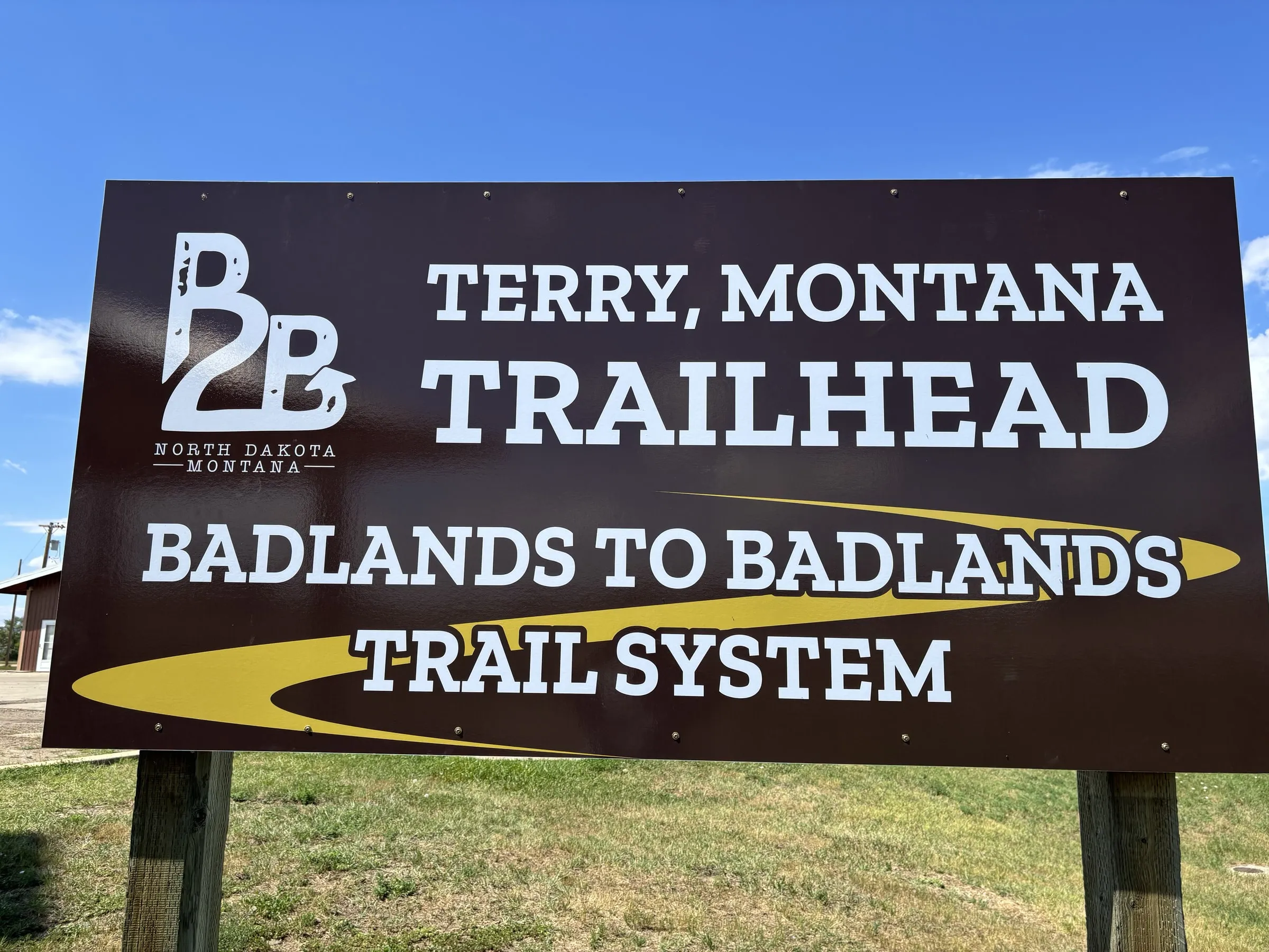 The Terry, Montana trailhead sign for the Badlands to Badlands trail system, under a blue sky